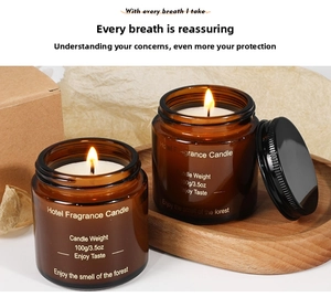 Detail of two amber glass scented candles with black lids and forest fragrance notes