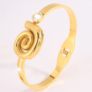 Detail of gold spiral bracelet featuring a sparkling white zircon and spring clasp