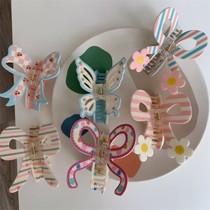6-piece set of butterfly and bow hair claws with colorful patterns in a white tray