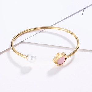 Detail view of gold flower bracelet featuring pink enamel petals and a round pearl