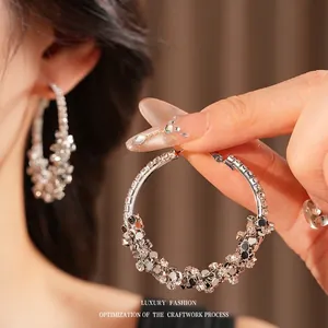 Boucles d'oreilles créoles argentées avec cristaux pavés portées par un mannequin