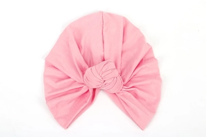 Detail shot of a soft pink elastic turban hat with a stylish front cross knot detail