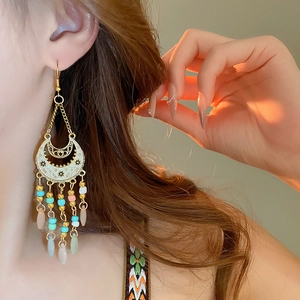 Detail of bohemian drop earrings with enamel moon and colorful beaded tassels