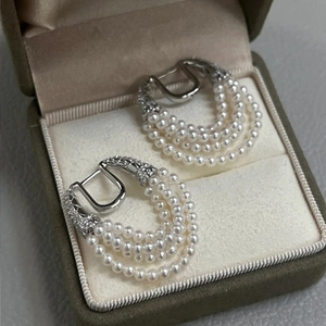 Close-up of pearl tassel hoop earrings with zircon accents in a beige velvet jewelry box