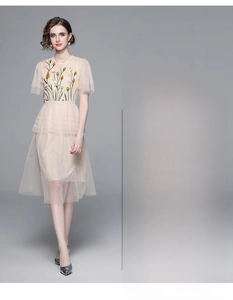 Detail of elegant mesh embroidery and high-waist tiered skirt on apricot dress