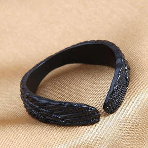 Macro shot of vintage black wing ring featuring detailed feather textures on gold silk