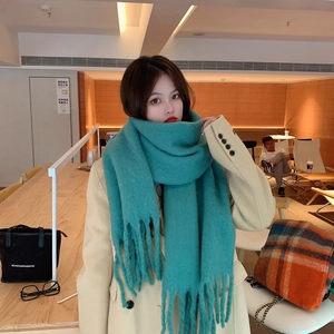 Stylish green mohair scarf with tassels shown worn on a model in a cafe setting