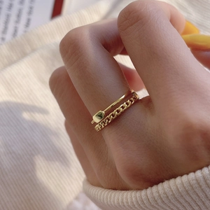 Detail of golden double-layer ring featuring a Cuban link band and small square buckle charm