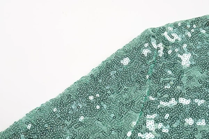 Detailed macro view of bright green sequins on fashion dress fabric with high shimmer