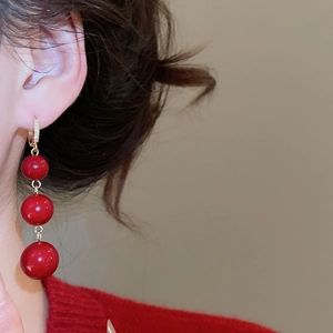 Close-up of red resin bead tassel earrings with gold plating and sparkling crystals