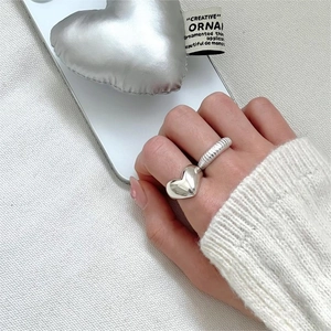 Detail of stacked 925 sterling silver heart ring and striped open band on model