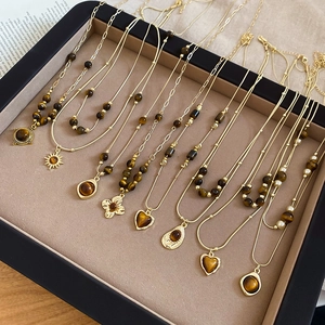Flat lay of multiple vintage gold flower necklaces with tiger eye stones on black velvet