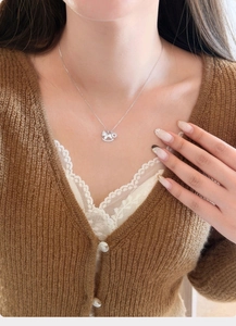 Silver horse necklace with zircons worn by a model over a cozy knit cardigan
