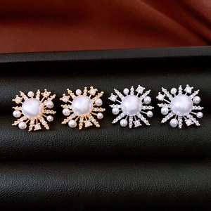 Close-up of pearl flower earrings in gold and silver finish on black leather case