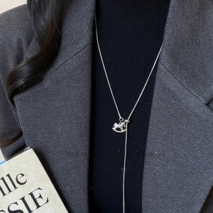 Close-up of adjustable silver rocking horse pendant necklace on a black sweater