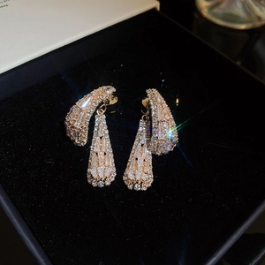Détail de boucles d'oreilles carrées dorées serties de zircons sur velours noir profond