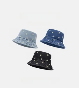 Detailed view of daisy embroidered denim bucket hats in light blue, dark blue and black