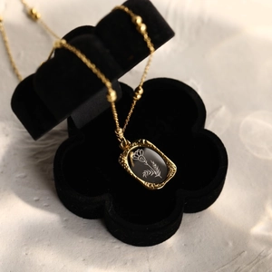 Vintage gold necklace with rose flower pendant inside a black velvet floral box