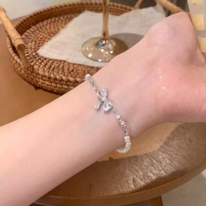 Macro detail of silver bow pearl bracelet with zircon stone on a female wrist