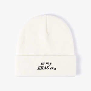 Detail of 'in my ERAS era' black embroidery on off-white knitted winter beanie