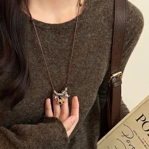 Detail of vintage wooden horse pendant necklace on brown sweater with starry metal rings
