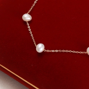 Elegant white freshwater pearl bracelet with thin gold chain on red velvet jewelry box