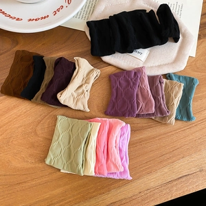 Close-up of knit hair scrunchies set in various colors with wavy texture and soft elastic fabric