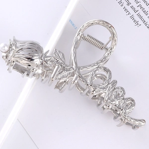 Macro view of silver metal hair claw featuring a rose bud with pearl and love script detail