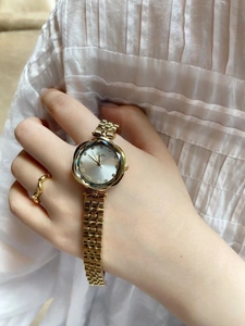 Elegant gold mesh strap watch with faceted glass dial shown on a woman wrist