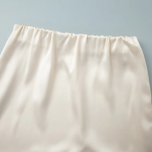 Detailed macro view of the elastic waistband on a champagne satin lace skirt