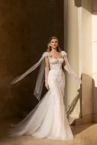 Dettaglio dell'abito da sposa a sirena bianco con ricami in pizzo e maniche in tulle rimovibili