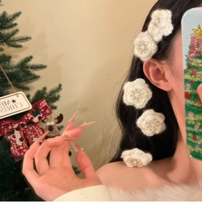 Detail showing five white knitted flower hair clips with pearls on a model side profile