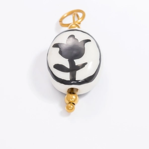 Detailed macro view of an oval white porcelain pendant with elegant black floral patterns