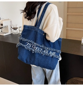 Détail du sac cabas en jean bleu avec franges effilochées et lettrage 7STREET
