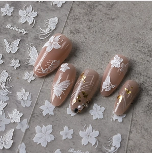 Detail of white embossed butterfly and floral nail stickers on pink manicure