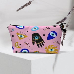 Detailed view of pink cosmetic bag with evil eye and hamsa hand motifs on a stand