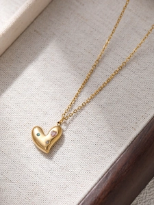 Dettaglio della collana in acciaio al titanio dorato con ciondoli in zircone a cuore