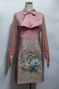 Detailed close-up of floral embroidery and lace bow on a pink vintage satin dress