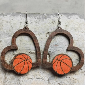 Detailansicht der herzförmigen Holzohrringe mit Basketball-Motiv auf Steinhintergrund