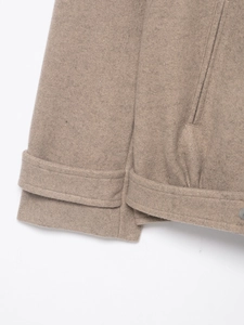 Detailed view of camel wool bomber jacket hem showing textured fabric and matte button