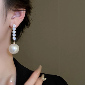 Close-up of model wearing elegant silver earrings with vertical rhinestones and round pearl