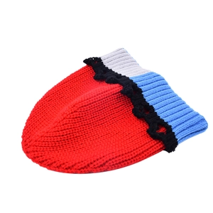 Gros plan détaillé sur la texture en tricot épais et le bord festonné de ce bonnet rouge