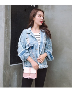 Close-up of heart charm crossbody bag paired with a distressed denim jacket on a model
