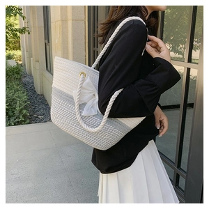 Detail of woven tote bag with a white bow and thick rope handles for summer fashion