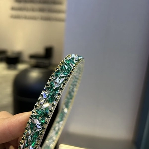 Macro shot of gold bracelet with green marquise stones and black gems