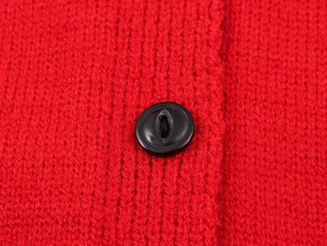 Detail of a bright red knit sweater showing texture and a black button closure