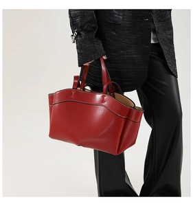 Detail of red leather tote bag with contrasting white stitching and double handles