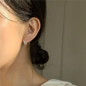 Close-up of minimalist silver four-prong stud earring with zircon worn by a model
