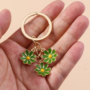 Close-up of golden keychain with three green daisy pendants and yellow flower centers