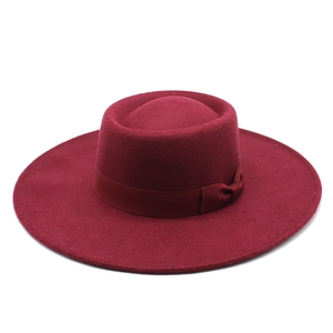 Detailed close-up of a burgundy wool felt fedora featuring a wide brim and elegant bow ribbon